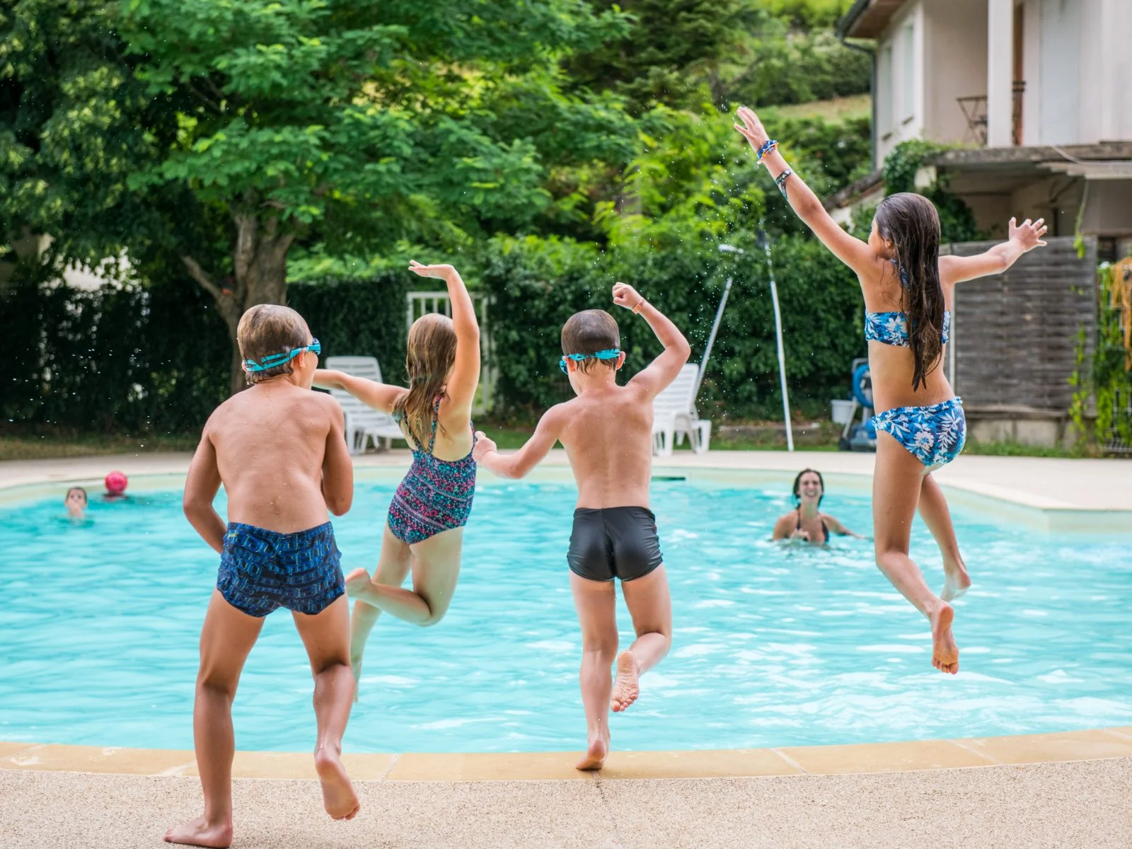 Quatre enfants sautent ensemble dans la piscine chauffée du camping